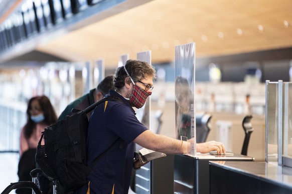 Ein Mann hinter eine Plastikscheibe beim Check-In Schalter aufgenommen anlaesslich des Schutzkonzeptes vom Flughafen Zuerich, aufgenommen am Donnerstag, 28. Mai 2020 in Zuerich. (KEYSTONE/Ennio Leanza ...