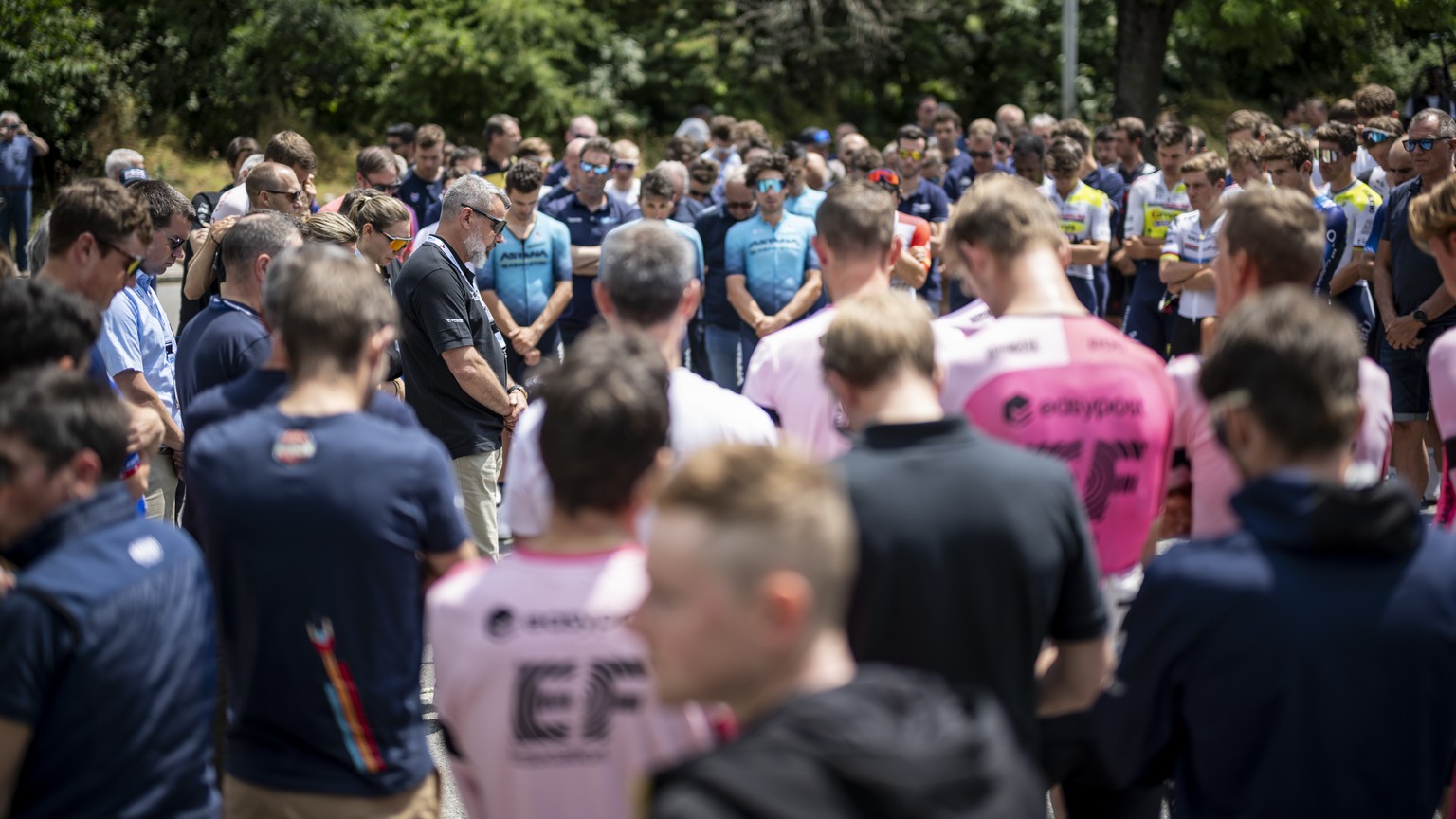 Event director Olivier Senn, center left, holds a minute of silence in honour of Gino Maeder from Switzerland of Bahrain-Victorious, who died following his crash the day before, at the 86th Tour de Su ...
