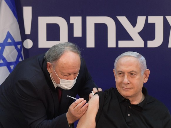 HANDOUT - Benjamin Netanjahu (r), Ministerpräsident von Israel, wird im Schiba-Krankenhaus gegen Corona geimpft. Foto: Amos Ben-Gershom/GPO/dpa - ACHTUNG: Nur zur redaktionellen Verwendung und nur mit ...