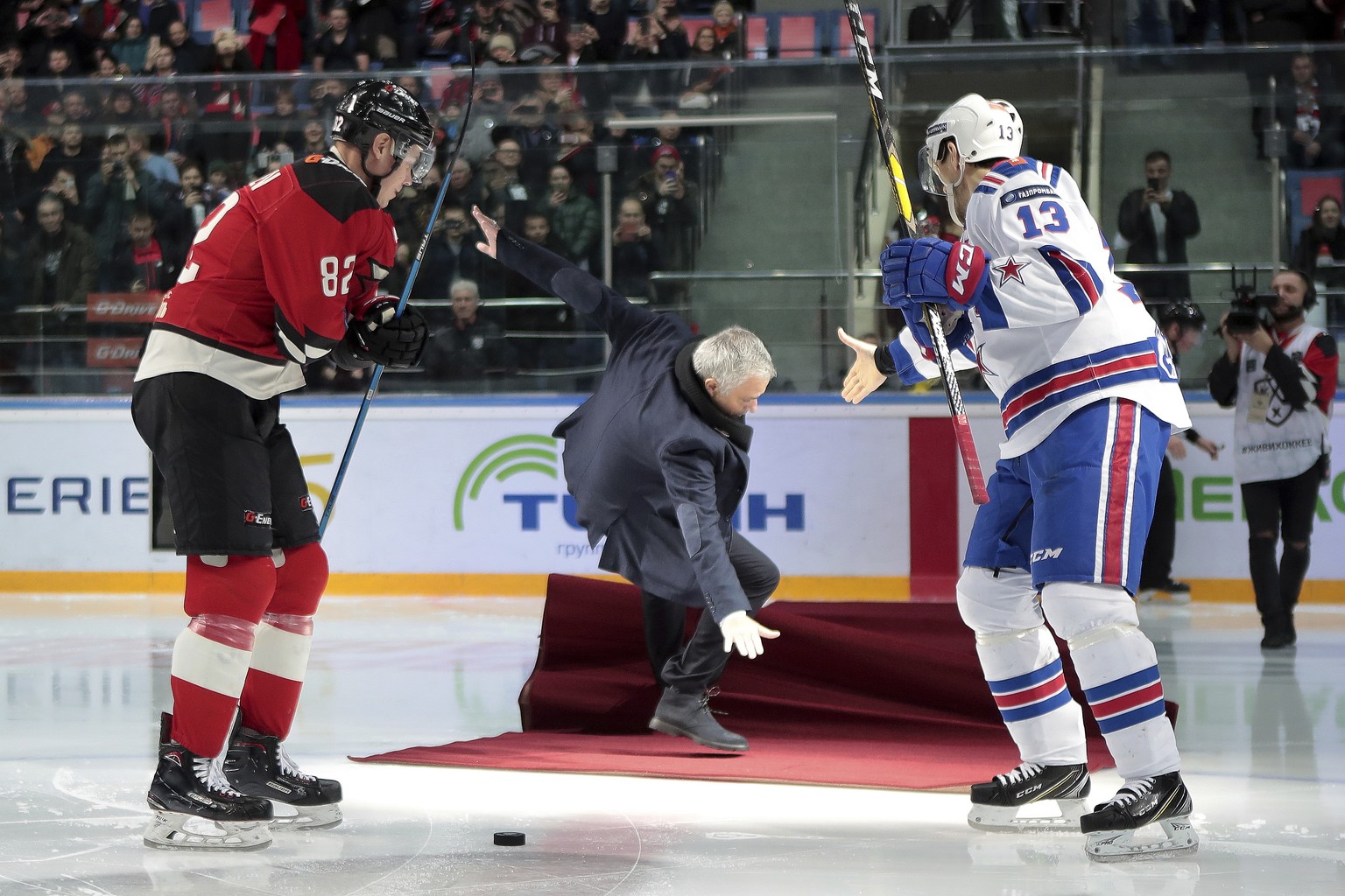 Former Manchester United coach Jose Mourinho, center, falls down after making the first puck drop as two-time Stanley Cup winner Pavel Datsyuk of SKA St. Petersburg, right, tries to help him at Monday ...