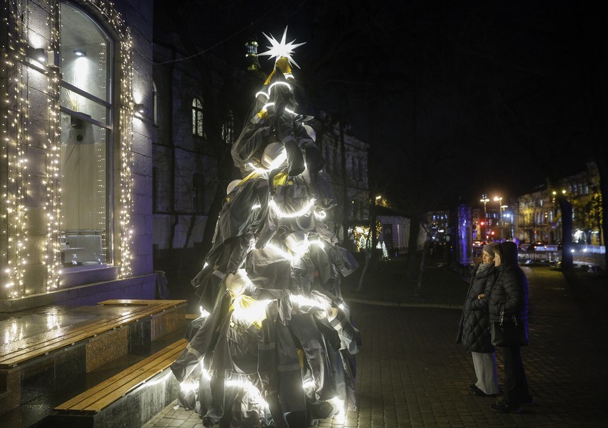 epa12609101 People stand near a symbolic Christmas tree dedicated to the nation's energy workers in downtown Kyiv, Ukraine, 22 December 2025, amid the Russian invasion. Made from uniforms of util ...