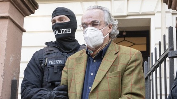 07.12.2022, Hessen, Frankfurt/Main: Bei einer Razzia gegen sogenannte «Reichsbürger» führen vermummte Polizisten, nach der Durchsuchung eines Hauses Heinrich XIII Prinz Reuß (2.v.r.) zu einem Polizeif ...