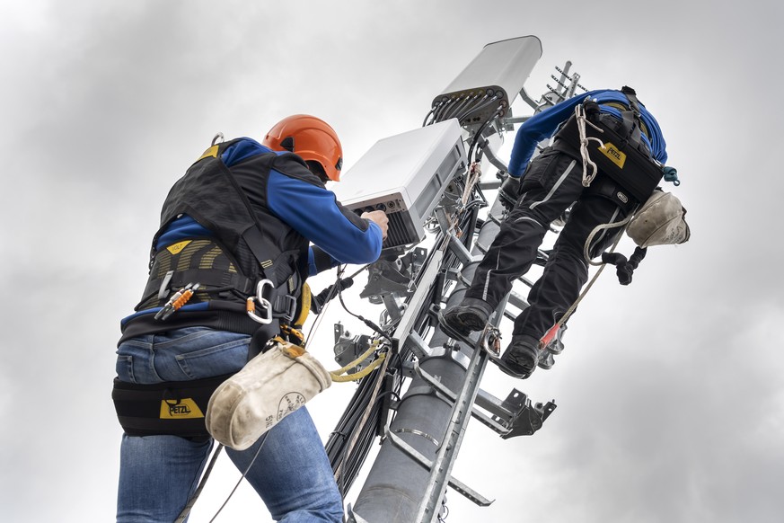 Deux employes de l&#039;entreprise Axians installent une antenne 5G de communication pour les mobiles sur un mat situe sur le toit d&#039;un immeuble du quartier de la Gradelle a Chene-Bougeries ce ve ...