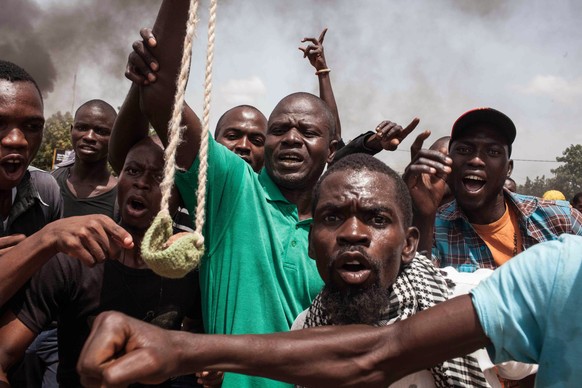 A Burkina Faso protestor holds a loaded slingshot as others gesture, in the city of Ouagadougou, Burkina Faso, Thursday, Sept. 17, 2015. While gunfire rang out in the streets, Burkina Fasos military  ...