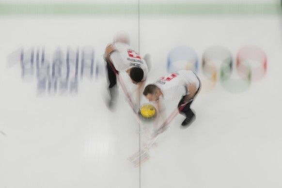 Switzerland's Pablo Lachat-Couchepin and Sven Michel sweep ahead of the stone during a men's curling round robin match against the United States at the 2026 Winter Olympics, in Cortina d ...