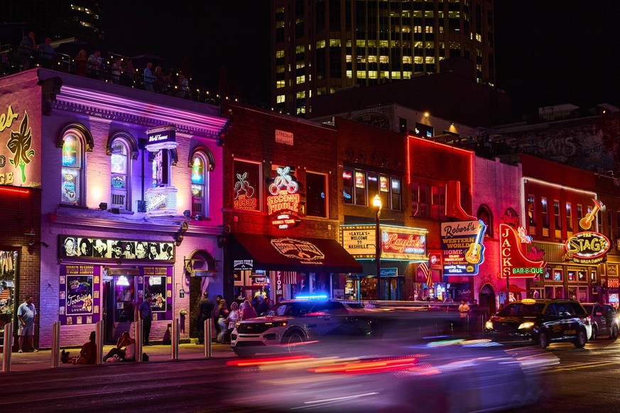 Neon Nightlife Buzz on Broadway Nashville Eye-Level View Bustling Nashville nightlife: vibrant neon lights illuminate Broadway Street as crowds enjoy iconic honky-tonks like The Stage and Robert s Wes ...