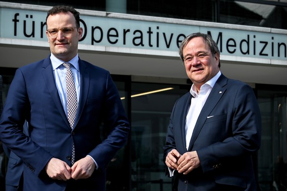 epa08333726 German Health Minister Jens Spahn (L) and Prime Minister of North Rhine-Westphalia, Armin Laschet (R) arrive for a joint visit to the University Hospital in Duesseldorf, Germany, 31 March  ...