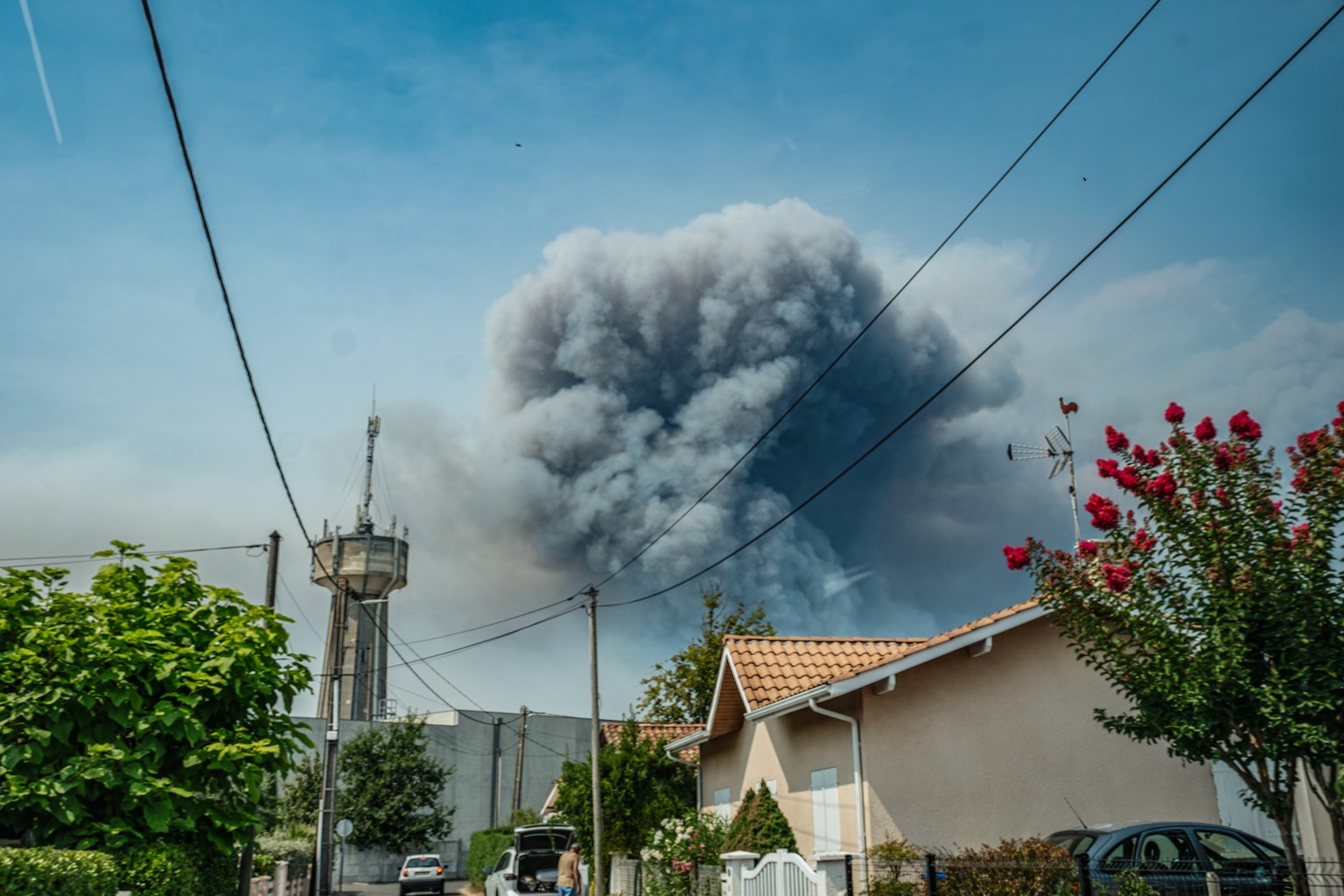 epa13131005 Smoke from a wildfire spreading on Cap Ferret peninsula is seen over houses in Andernos, south-western France, 24 July 2026. French Interior Minister Laurent Nunez confirmed that around 40 ...