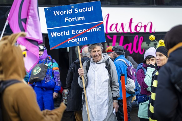 epa12654987 A protester holds a placard reading 'World Social Forum' during a demonstration of the collective 'Strike WEF' before the annual meeting of the World Economic Forum (WE ...