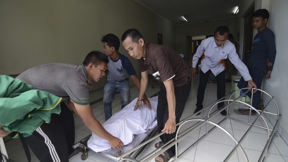 In this Monday, April 9, 2018, photo, family move the body of a victim who died from drinking poisonous bootleg liquor at a hospital in Cicalengka, West Java, Indonesia. Indonesian authorities say mor ...