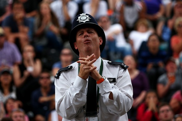 LONDON, ENGLAND - JULY 12: A policeman reacts as he watches the Gentlemen&#039;s Singles final match between Novak Djokovic of Serbia and Roger Federer of Switzerland on Murray Mound on day 13 of the  ...