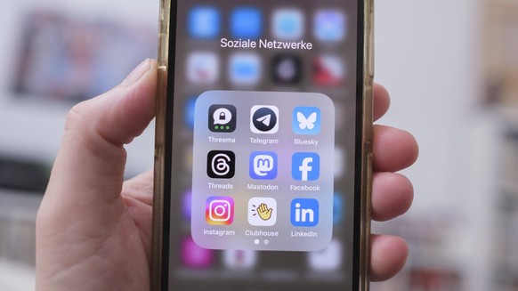 Eine Hand hält ein Mobiltelefon auf dem die Logos von verschiedenen social media Anbietern zu sehen sind *** Hand holds a mobile phone on which the logos of various social media providers can be seen  ...