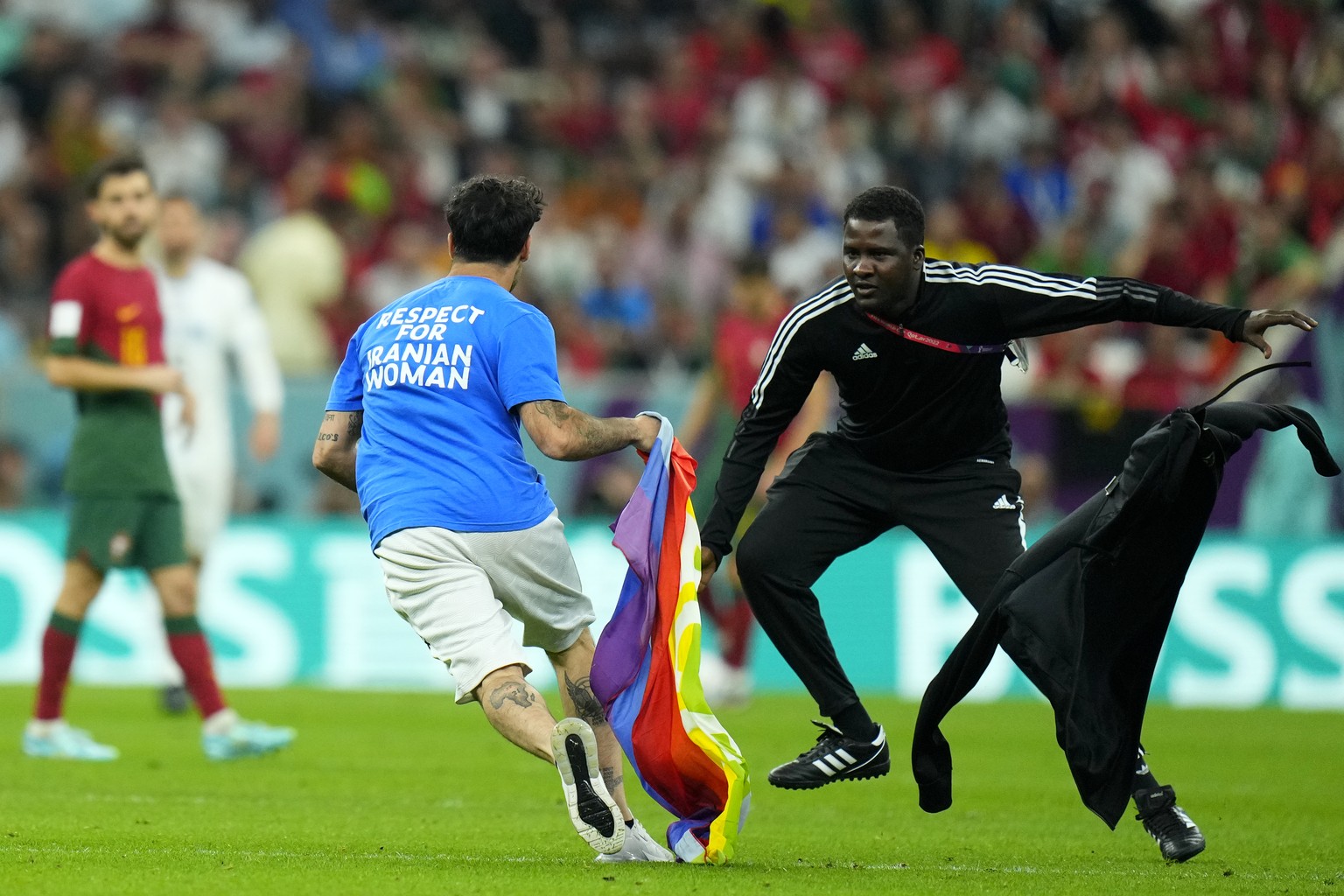 A pitch invader runs across the field with a rainbow flag during the World Cup group H soccer match between Portugal and Uruguay, at the Lusail Stadium in Lusail, Qatar, Monday, Nov. 28, 2022. (AP Pho ...