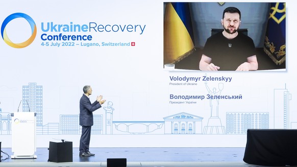 epa10051413 Swiss President and Minister of Foreign Affairs Ignazio Cassis (L) introduces Ukrainian President Volodymyr Zelenskyy delivering a speech by video conference during the Ukraine Recovery Co ...