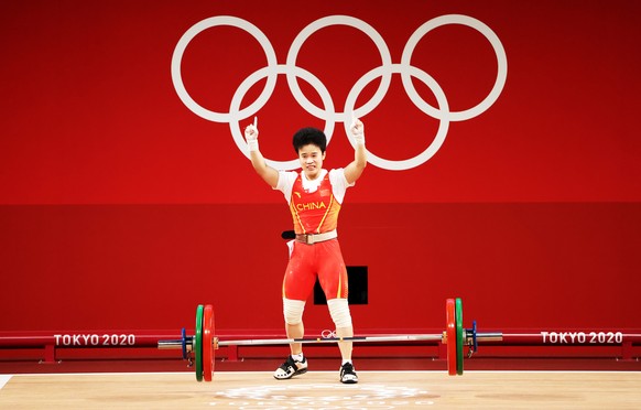 epa09361021 Hou Zhihui of Cina celebrates after an attempt in the Group A Women&#039;s 49kg - Snatch during the Weightlifting events of the Tokyo 2020 Olympic Games at the Tokyo International Forum in ...