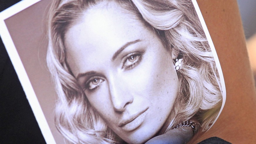 File: In this Tuesday, Feb. 19, 2013 file photo a mourner holds a program with a photo of Reeva Steenkamp at her funeral in Port Elizabeth, South Africa. A sobbing Oscar Pistorius refused to look at a ...