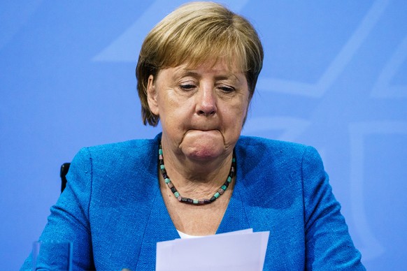 epa09408738 German Chancellor Angela Merkel looks on during a press conference after a virtual meeting with German State Premiers about the current coronavirus situation, at the Chancellery in Berlin, ...