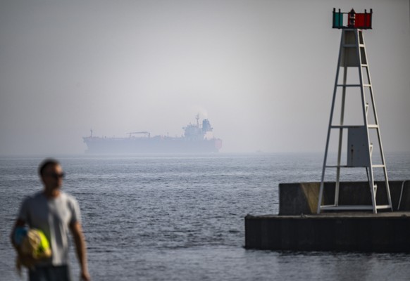KEYPIX - epa12930088 A man walks backdropped by the ship Jin Hui, which was boarded by the Swedish Coast Guard, in the haze outside Trelleborg, Sweden, 03 May 20226. This is the fifth time the Swedish ...