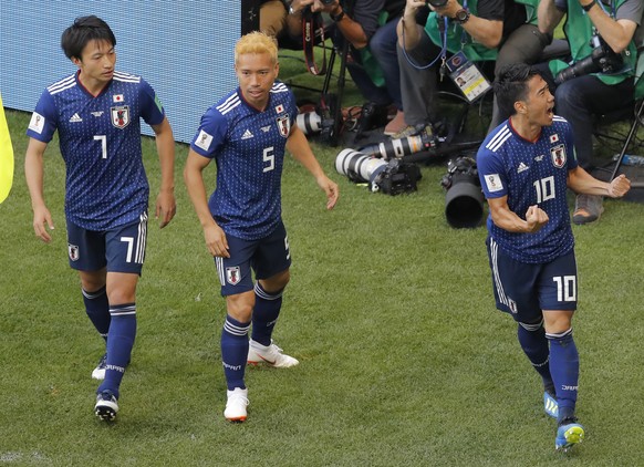 Japan's Shinji Kagawa, right, celebrates with Yuto Nagatomo, center, and Gaku Shibasaki, left, scoring opening goal with Japan's head coach Akira Nishino, left, during the group H match betw ...