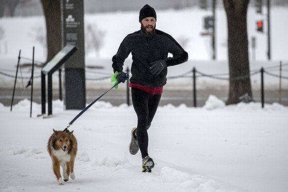 epa05847682 A jogger and his dog navigate a snow covered path on the National Mall in Washington, DC, USA, 14 March 2017. While New York City and Boston had been issued a blizzard warning, that has be ...