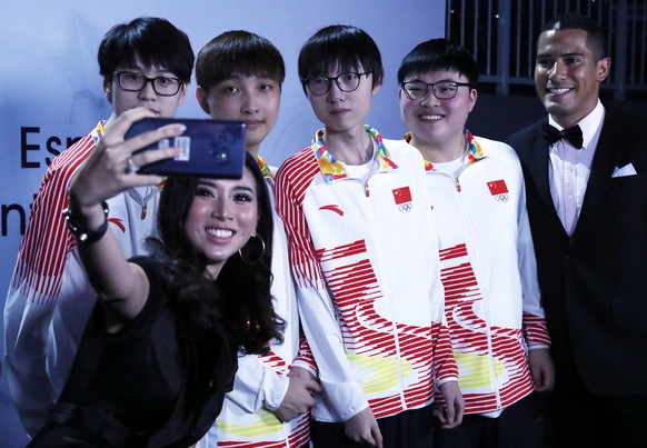 epa06980612 Esports finals winners team China pose for selfies with presenters after their win over South Korea in the finals of the League of Legends esports tournament, included as an official demon ...