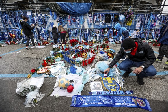Fans look at the memorabilia hanging on the gates of the San Paolo stadium in Naples, Italy, Sunday, Nov. 29, 2020, as the pilgrimage of fans to the stage where soccer ace Diego Armando Maradona perfo ...