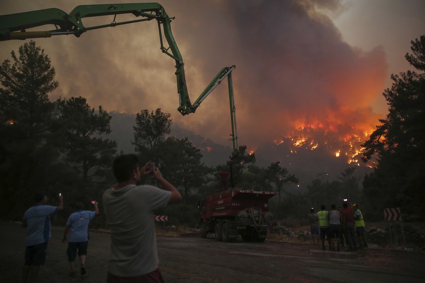 People watch an advancing fire that rages Cokertme village, near Bodrum, Turkey, Monday, Aug. 2, 2021. For the sixth straight day, Turkish firefighters battled Monday to control the blazes that are te ...