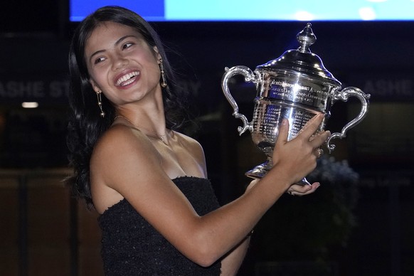 Emma Raducanu, of Britain, poses outside Arthur Ashe Stadium with the championship trophy after she defeated Leylah Fernandez, of Canada, in the women&#039;s singles final of the US Open tennis champi ...