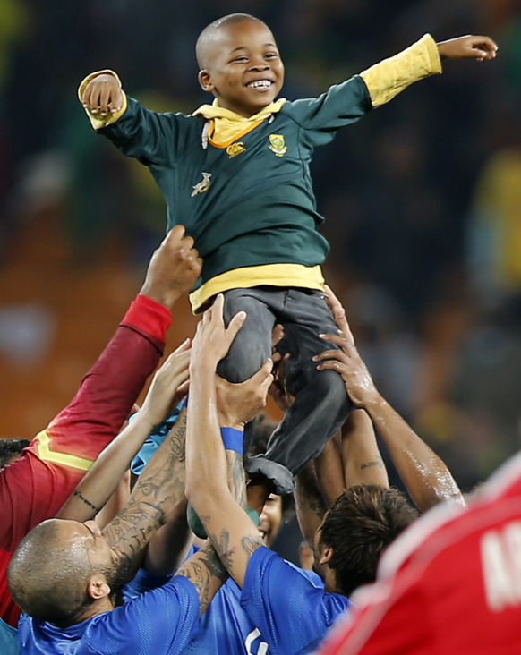 Der kleine südafrikanischer Junge wird von den Brasil-Stars in den Himmel gehoben.