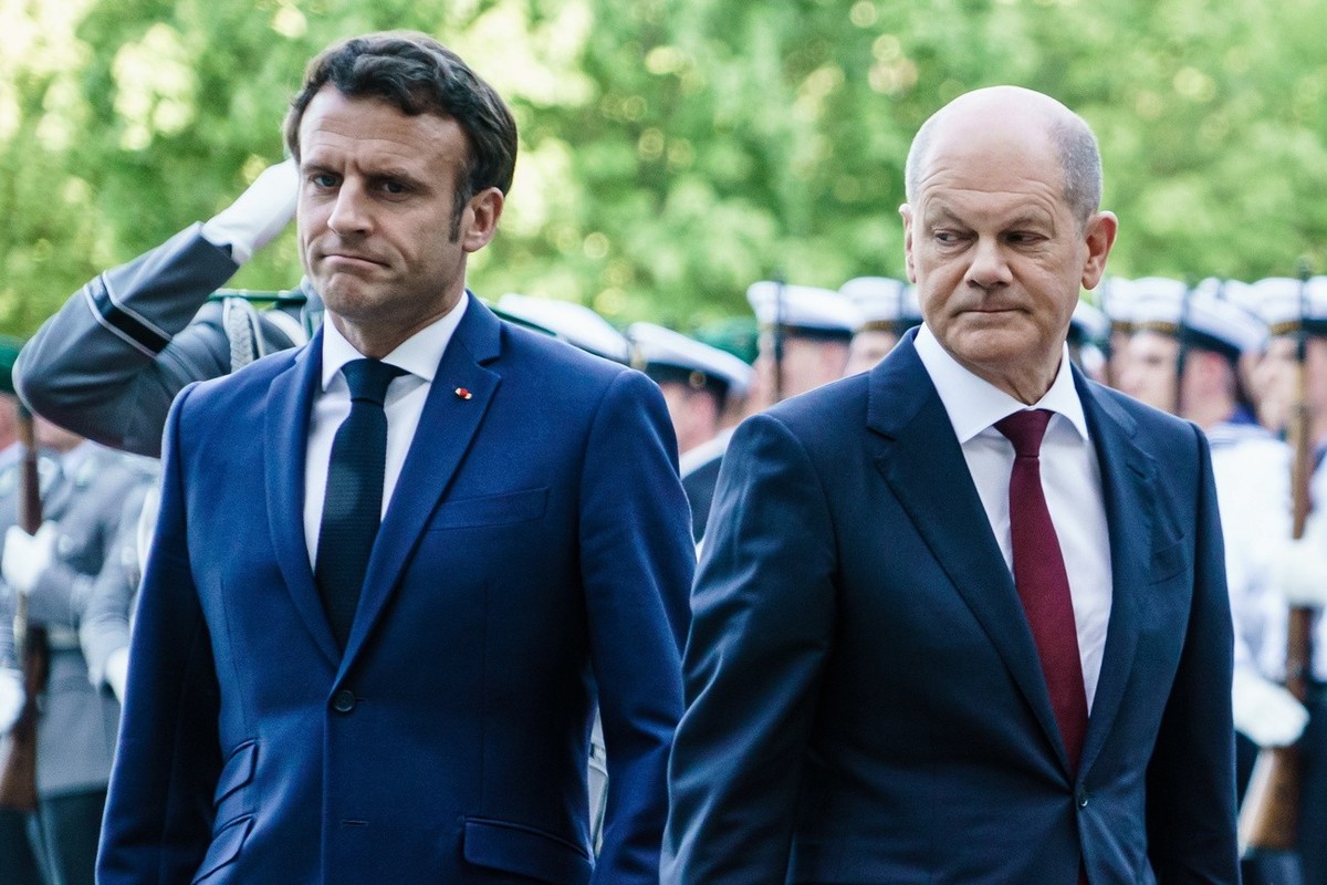 epa09936617 German Chancellor Olaf Scholz (R) walks with French President Emmanuel Macron during a reception with military honors at the Chancellery in Berlin, Germany, 09 May 2022. Chancellor Scholz  ...