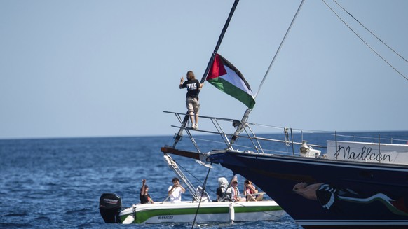 Climate activist Greta Thunberg stands near a Palestinian flag after boarding the Madleen boat and before setting sail for Gaza along with activists of the Freedom Flotilla Coalition, departing from t ...