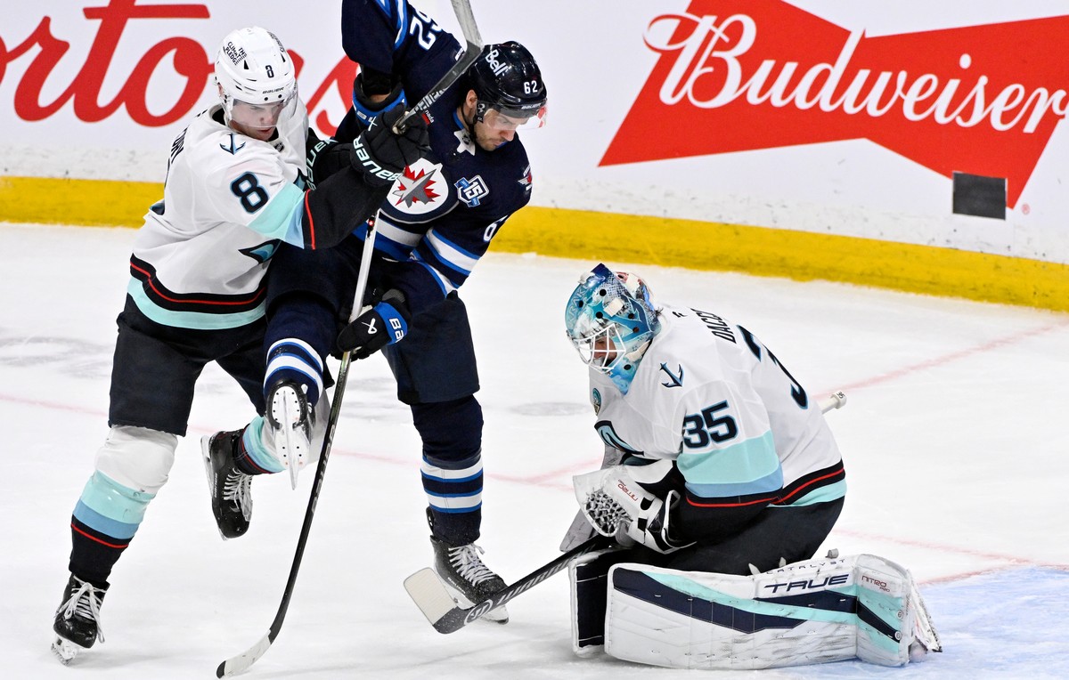 Winnipeg Jets' Nino Niederreiter (62) is checked by Seattle Kraken's Cale Fleury (8) as Kraken goaltender Joey Daccord (35) makes a save during second-period NHL hockey game action in Winnip ...