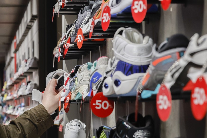 epa10393898 A shopper takes a look at sneakers with reduced prices in a department store after its opening, in Madrid, Spain, 07 January 2023. January sales begin on 07 January in most Spanish stores, ...