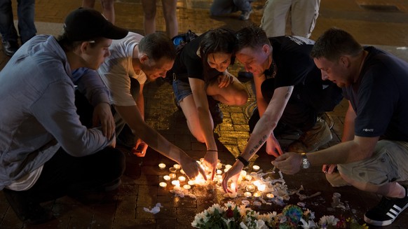 epaselect epa06141576 People place candles as they gather during a vigil in Charlottesville, Virginia, USA, 12 August 2017. According to media reports at least one person was killed and 19 injured aft ...