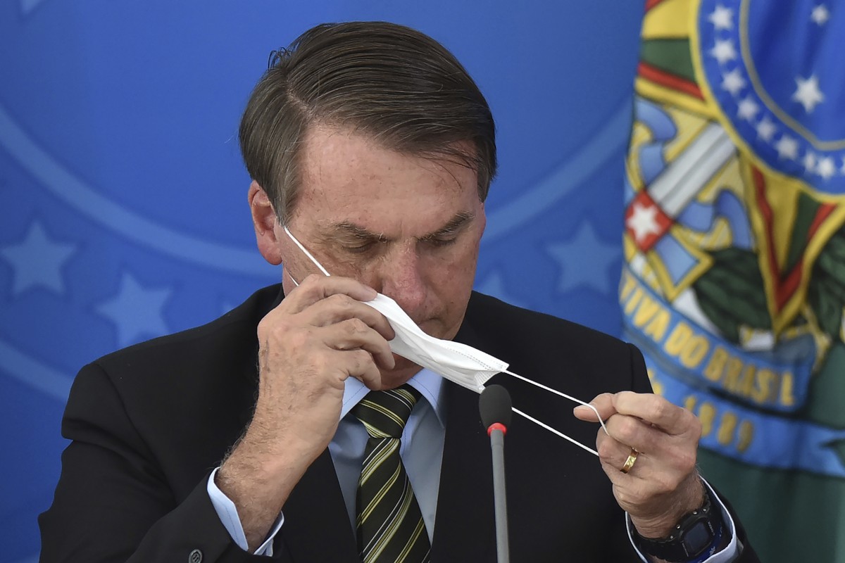 Brazil's President Jair Bolsonaro puts on a mask during a press conference on the new coronavirus at the Planalto Presidential Palace in Brasilia, Brazil, Wednesday, March 18, 2019. For most peop ...