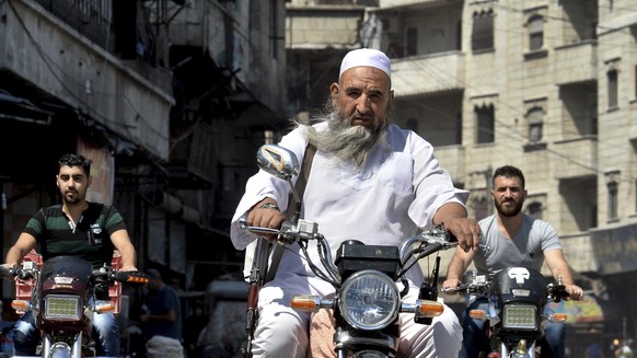 In this Monday, Sept. 10, 2018 photo, an armed man rides his motorcycles in the centre of the northern city of Idlib, Syria. Syrian government forces, backed by Russia and Iran, have been massing troo ...