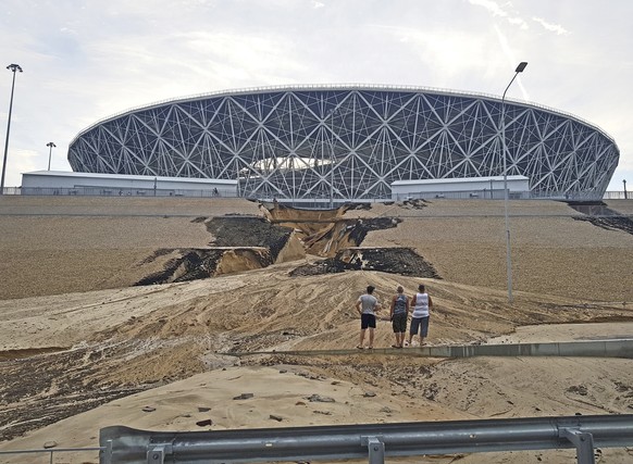 Three men look at a major landslip on an embankment after a heavy rain next to the Volgograd Arena, one of Russia's World Cup venues in Volgograd, Russia, Sunday, July 15, 2018. The stadium, built on  ...