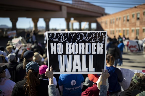 epa07323122 A protester holds a sign near the border after a group marched to protest a proposed wall being built along the border with Mexico in El Paso, Texas, USA, 26 January 2019. EPA/IVAN PIERRE  ...