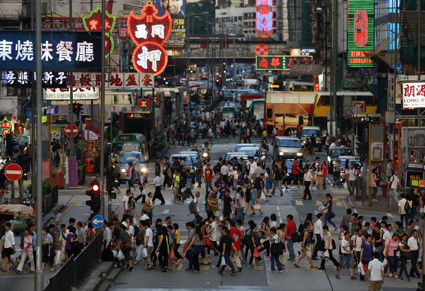 In this Sept. 10, 2014, photo, pedestrians cross the road in the Hong Kong shopping district of Mongkok during rush hour. On packed subways and crowded streets, billions of people worldwide participat ...