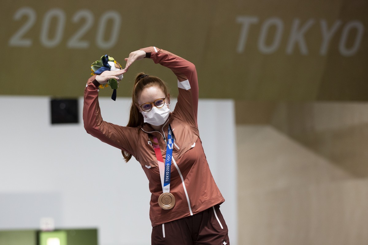 Nina Christen of Switzerland celebrates on the podium after winning the bronze medal in the women's shooting 10m air rifle final at the 2020 Tokyo Summer Olympics in Tokyo, Japan, on Saturday, Ju ...