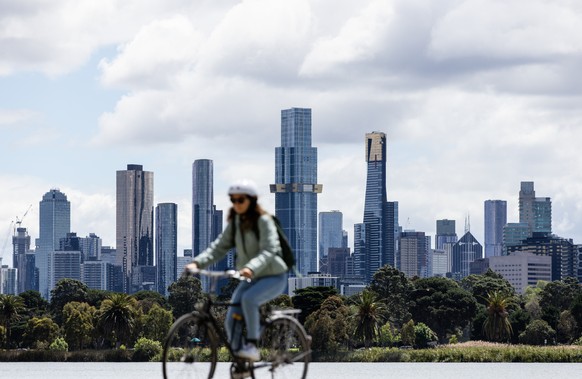 epa10272405 A cyclist rides in front of the skyline in Melbourne, Victoria, Australia, October 29, 2022. According to the Australian Government Bureau of Meteorology, widespread showers and storms are...