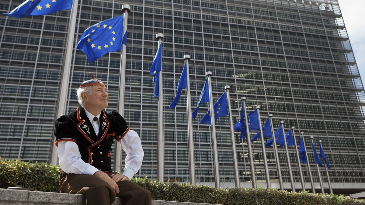 Flags of the European Union wave in front of the European Commission building in Brussels, June 8, 2011, while "Mister Swiss", dressed in a traditional Swiss costume, looks on. He is on his  ...