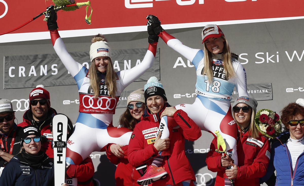 Switzerland's Lara Gut-Behrami, winner of an alpine ski, women's World Cup downhill, top right, celebrates with second-placed Switzerland's Corinne Suter, and the Swiss team, in Crans M ...