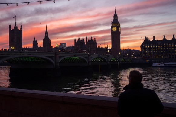 FILE - A man walks along the south bank of the River Thames backdropped by the Elizabeth Tower, known as Big Ben, of the Houses of Parliament, in London, Tuesday, Jan. 17, 2023. (AP Photo/Kin Cheung,  ...