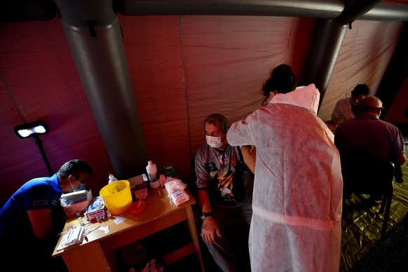 epa09234583 A man (C, sitting) receives an injection of ? vaccine against COVID-19 at a temporary tent built in a park of Sofia, Bulgaria, 29 May 2021. Medical teams from the municipal hospitals will  ...