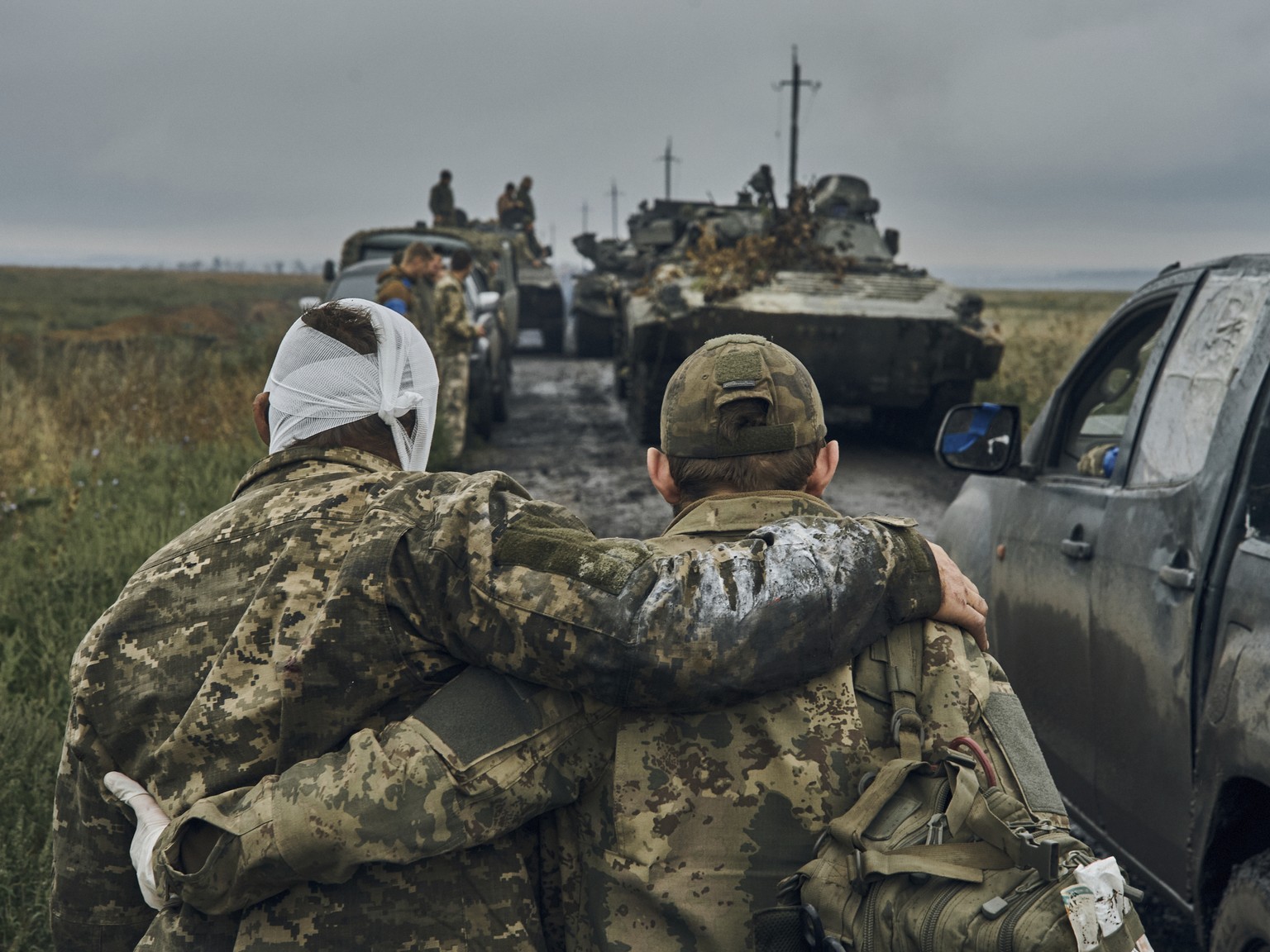 A Ukrainian soldier helps a wounded fellow soldier on the road in the freed territory in the Kharkiv region, Ukraine, Monday, Sept. 12, 2022. Ukrainian troops retook a wide swath of territory from Rus ...