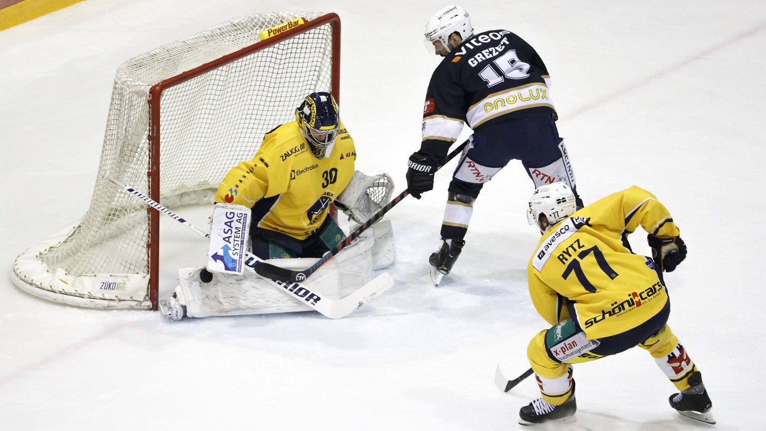 Langenthal&#039;s goaltender Philip Wuethrich, left, saves a puck past La Chaux-de-Fonds&#039; forward Samuel Grezet, center, and Langenthal&#039;s defender Philippe Rytz #77, during the third leg of  ...