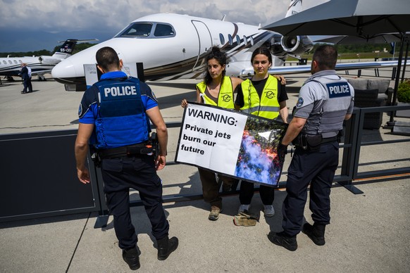 Police officers evacuate environmental activists of Stay Grounded and Greenpeace as they protest around a aircraft during the European Business Aviation Convention and Exhibition (EBACE), at the Genev ...