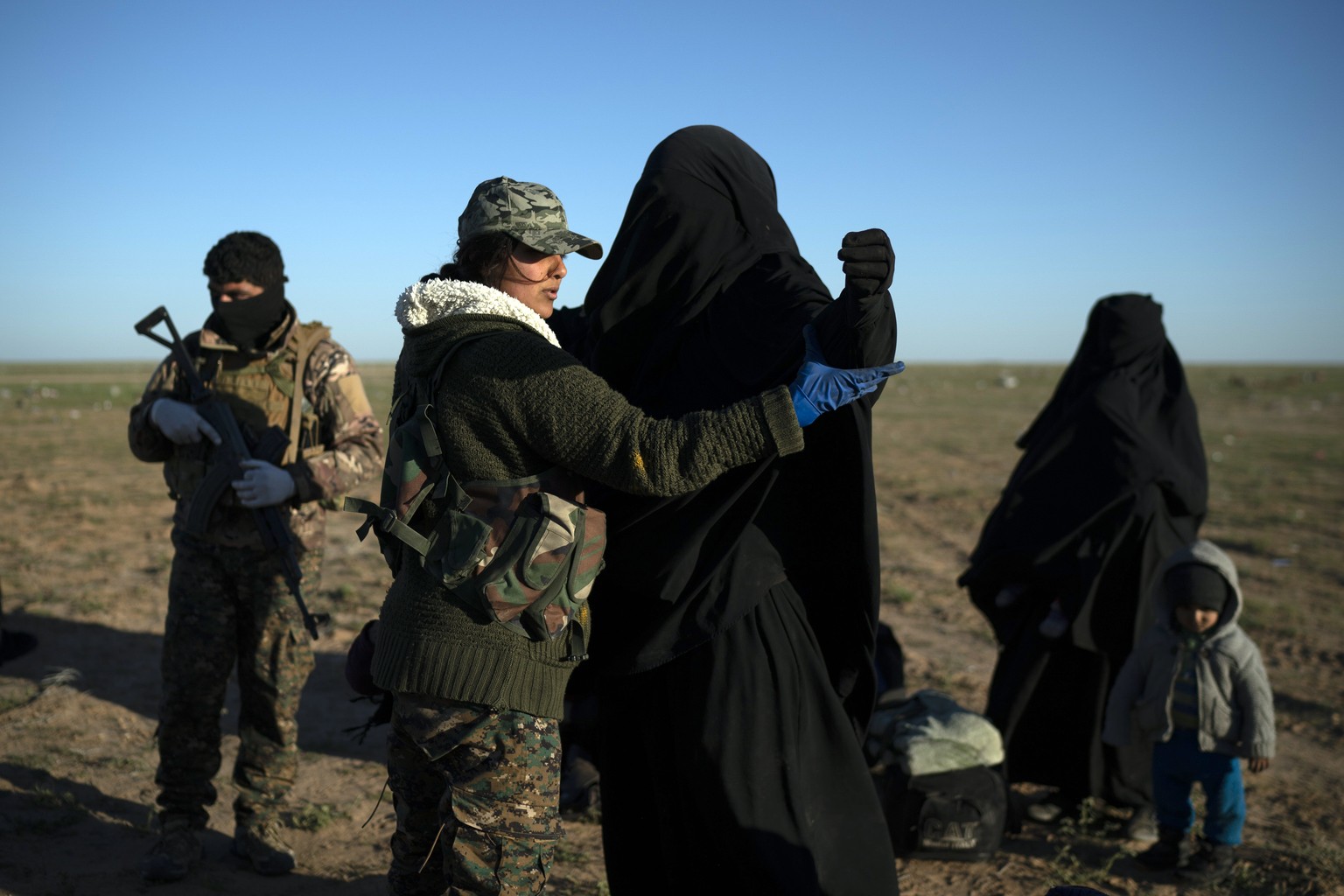 A woman is frisked by a U.S.-backed Syrian Democratic Forces (SDF) fighter at a screening area after being evacuated out of the last territory held by Islamic State militants, in the desert outside Ba ...