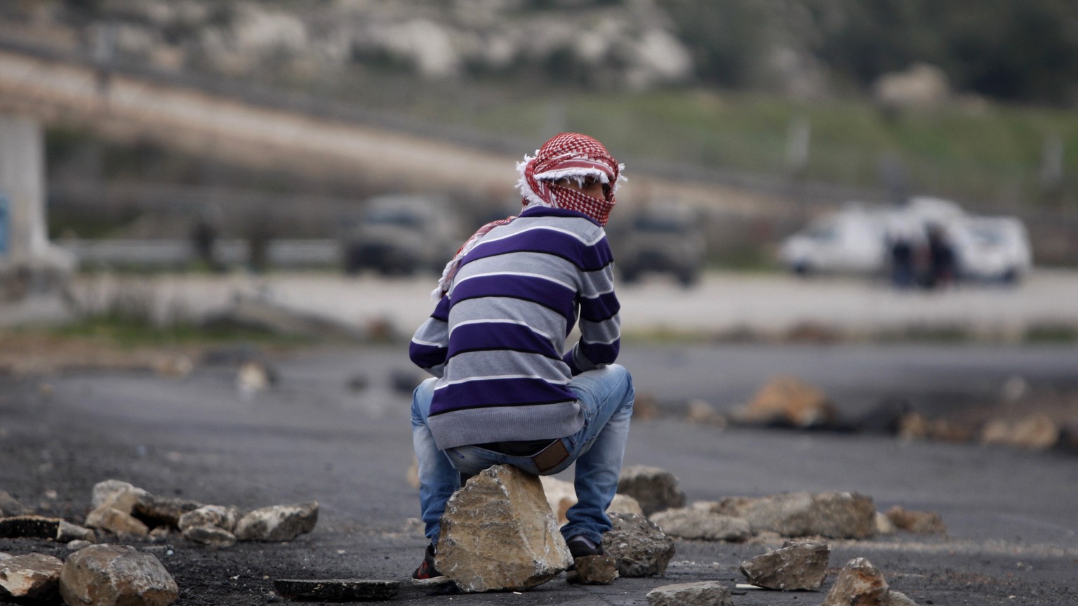 FILE - A masked Palestinian sits during a support rally for the Palestinian prisoners, outside Ofer, an Israeli military prison near the West Bank city of Ramallah, Friday, March 1, 2013. Israel&#039; ...